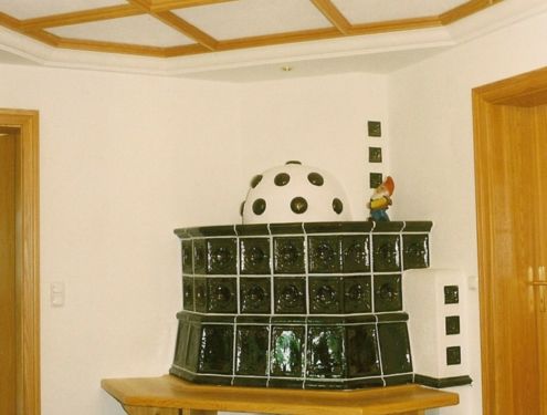 Kachelofen mit Kuppel mit Holzsitzbank in klassischem Ofengrün