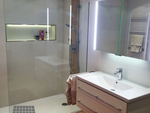 Zeitloses Badezimmer mit Dekorstreifen an der Duschrückwand und Duschnische für Shampoo etc.